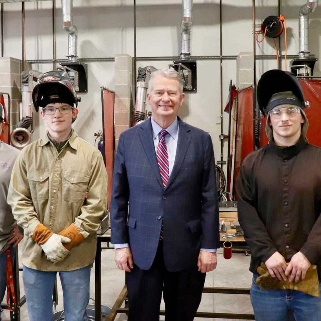 Governor Brad Little standing with 2 welders