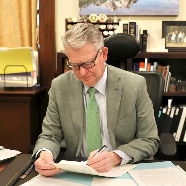 Governor Brad Little reading and signing documents at a desk